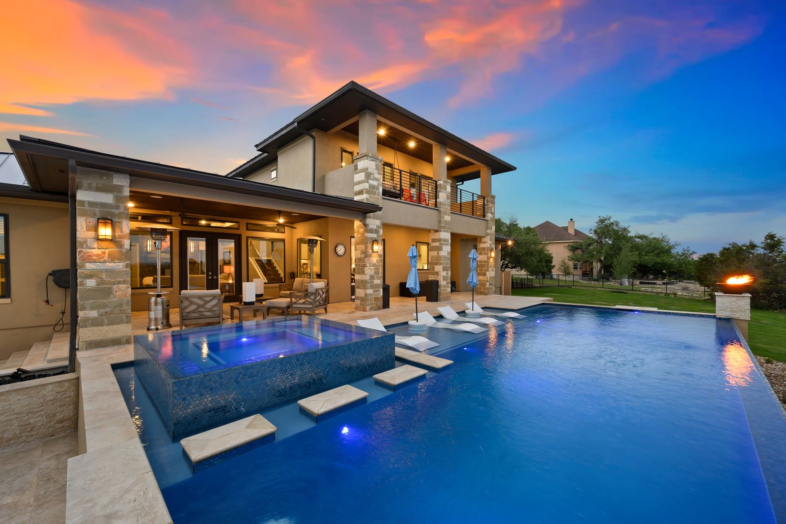 Backyard pool and covered outdoor living space lit at sunset